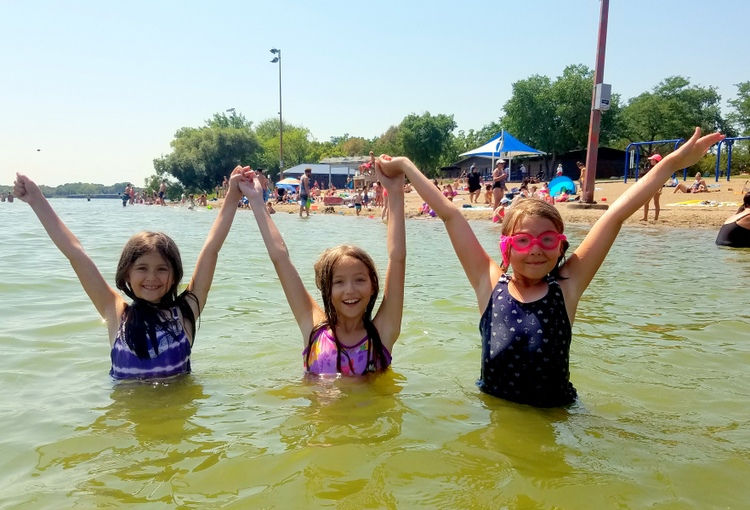 Three girls playing in the water at Lake Nokomis Beach in Minneapolis, MN