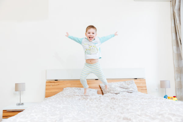 Preschool child jumping on a bed