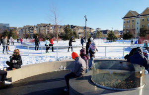 Skaters warming by the firepit at the Central Park Ice Loop in Maple Grove, Minnesota