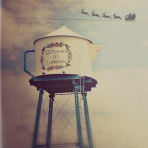 Water tower in Lindstrom, Minnesota with shadow of Santa and sleigh behind it. "Velkommen to Lindstrom"