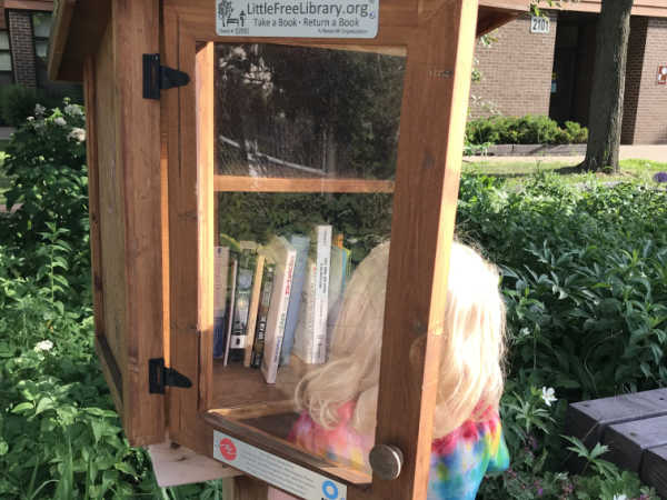 Girl perusing Little Free Library offerings