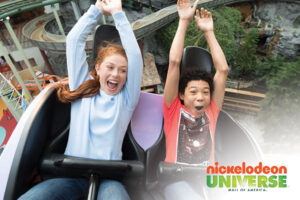 red-haired girl, black haired boy riding rollercoaster with arts up at nickelodeon universe