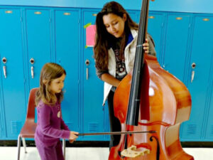 Girl tries out a bass at a Music & Melody Makers event in St. Paul, Minnesota