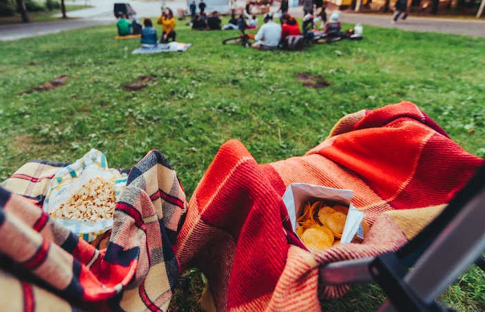 Camp chairs with wool blankets and movie treats ready for an outdoor movie in a park