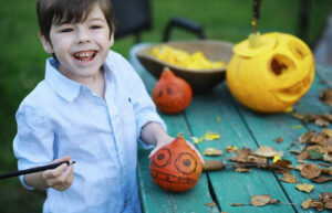 Boy crafting with pumpkins and gourds on a blue picnic table