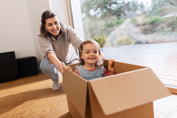 Mother pushing 2-year-old plaint in an empty box