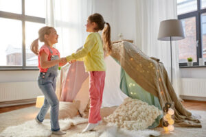 Two girls dancing in front of a blanket tent