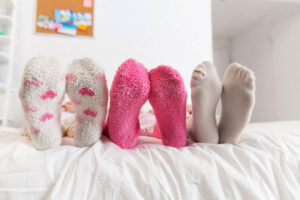 Three kids feet with socks on a bed