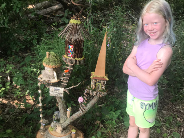 Girl standing next to fairy house in Westwood Hills Nature Center, Trail of Small Wonders, St. Louis Park, MN