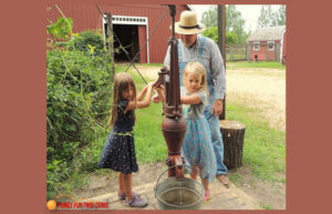 Girls learning how to pump water at Eidem Farm in Minnesota