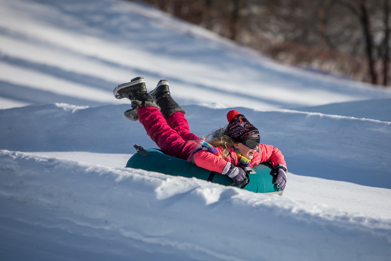 Girl snowtubing down a hill in Elm Creek Park, Maple Grove, Minnesota.
