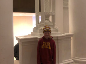 Girl standing in front of marble column at Northrop Memorial Auditorium in Minneapolis, MN.