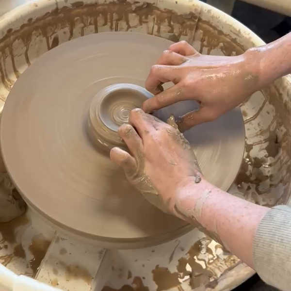 Two hands on a pottery wheel shaping clay at Dock 6 Pottery in Saint Anthony, Minnesota